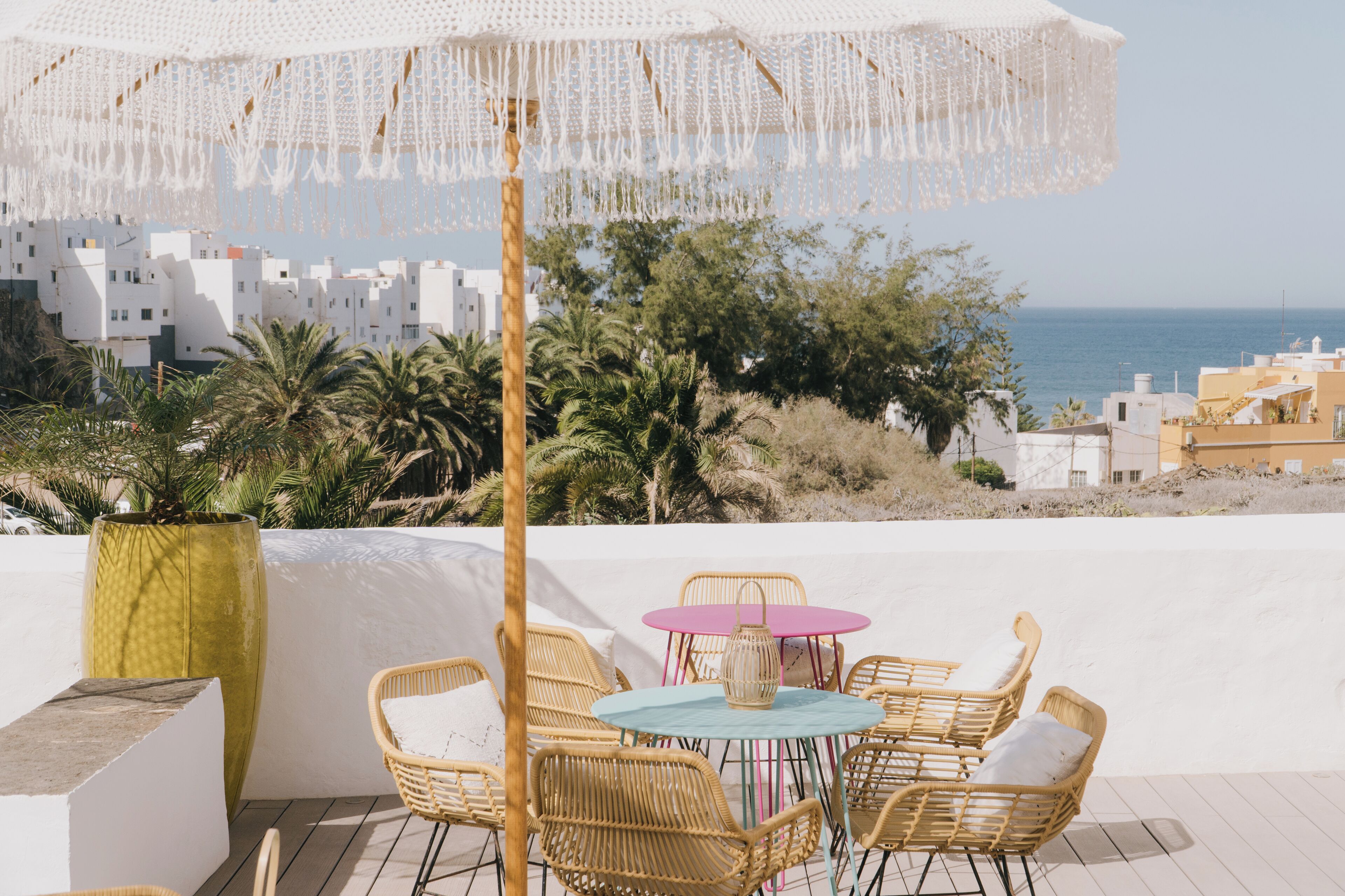 A terrace with wicker furniture, a table, and a hanging white umbrella.