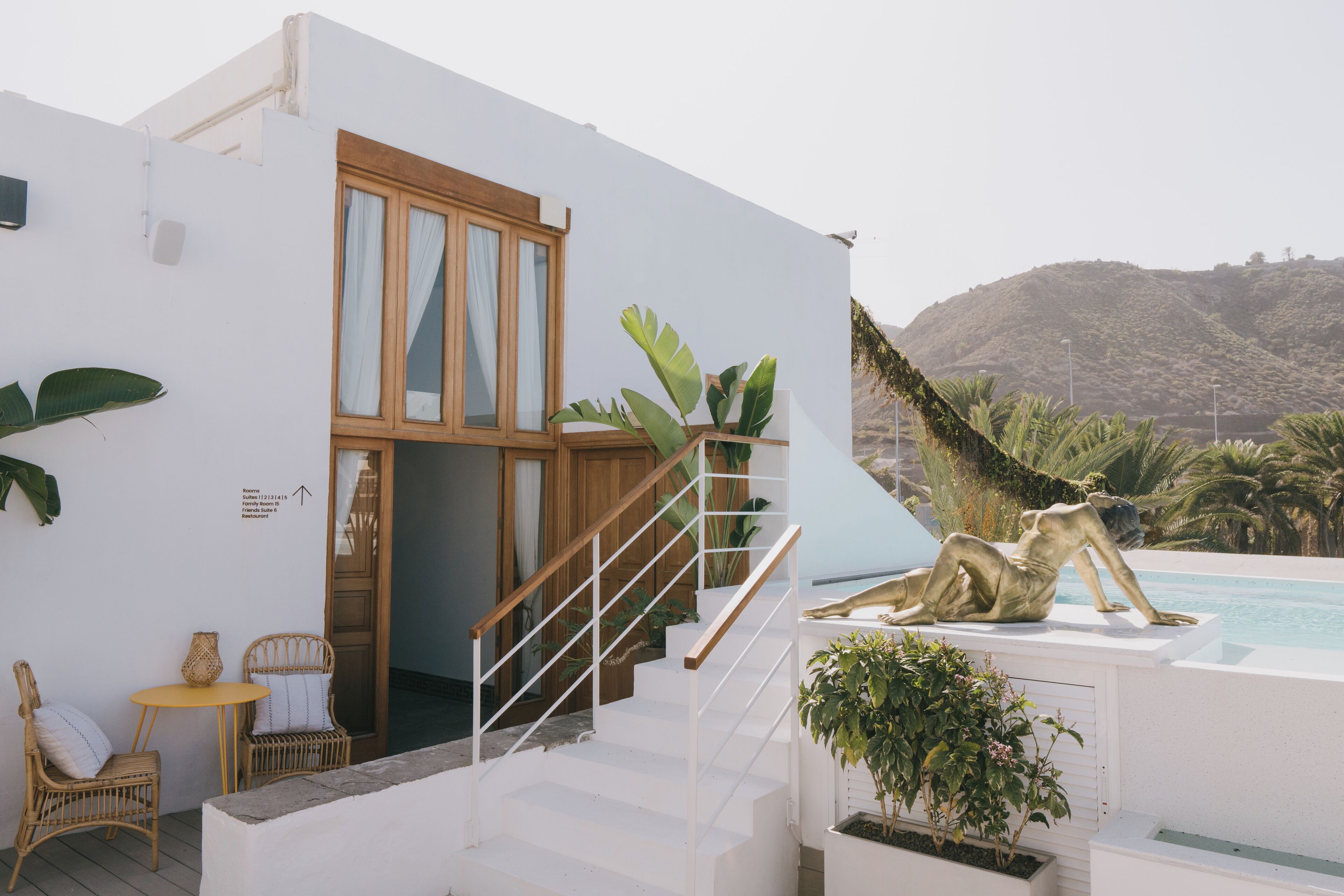 A modern white building with a wooden staircase leading to a pool area.