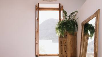 A bedroom with a wooden bed, a large window, a wooden wardrobe, and a mirror.