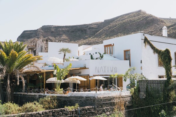 Un edificio blanco con un letrero que dice "NATIVO" y un área de piscina con sombrillas.