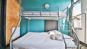 A bunk bed room with a window, a radiator, and a door. - Studio 95 - Shared & Private Rooms (Swansea)