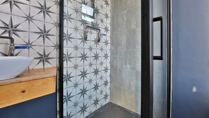 A modern bathroom with a geometric tile backsplash, a white sink, and a shower area. - Studio 95 - Shared & Private Rooms (Swansea)