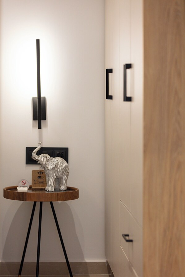 Una habitación de hotel moderna con un aparador de madera, una escultura decorativa de elefante, una lámpara de pared y una puerta con picaporte.