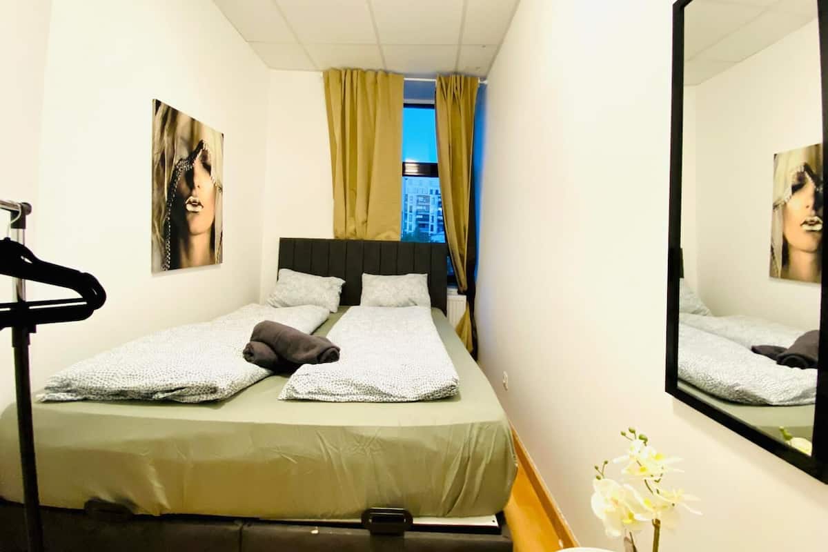 A hotel room with a bed, a mirror, and a window with curtains.