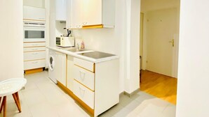 A modern kitchen with white cabinetry, a built-in oven, microwave, and sink. There is a small dining table with chairs. - Sweet 3BR Apt in a Quiet Neighborhood (Vienna)