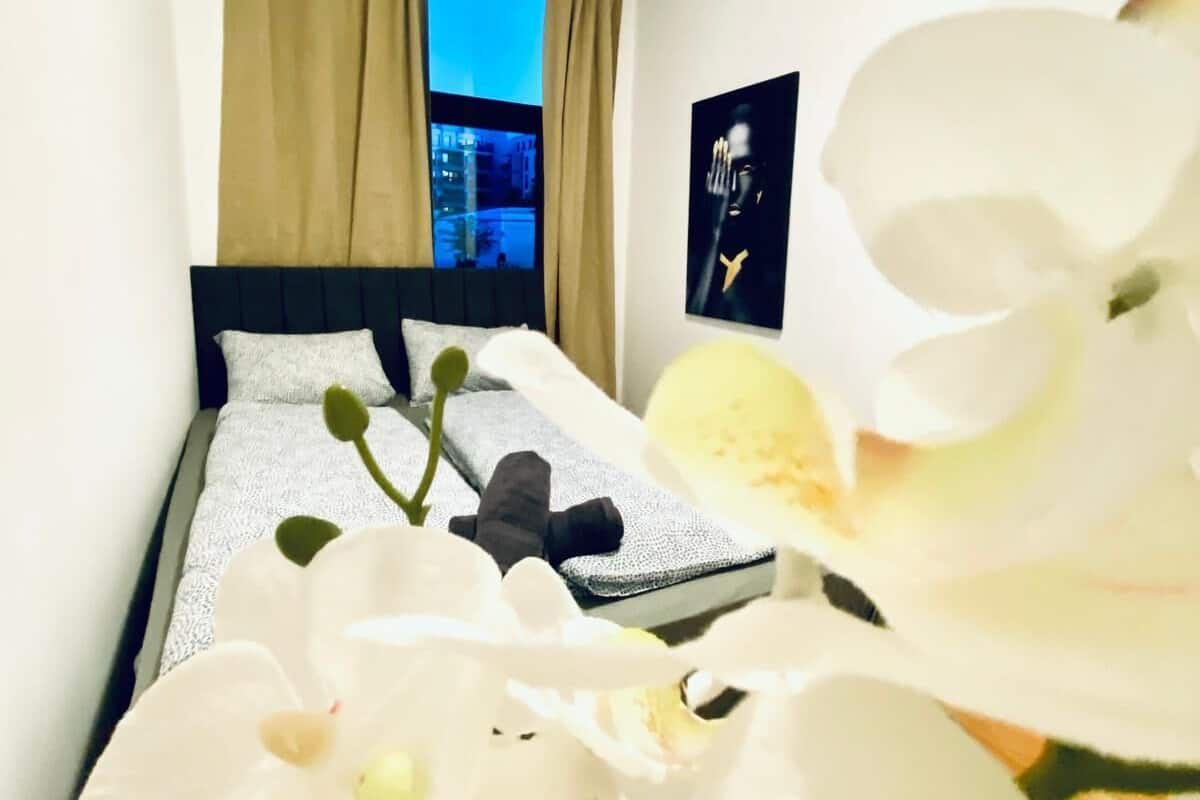 A hotel room with a bed, a window with curtains, and a poster on the wall.