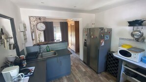 A compact kitchen with a sink, a refrigerator, a microwave, and a coffee maker.