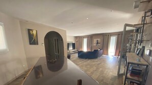 A spacious living area with a large dining table, a sofa, and a TV.