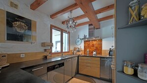 Una cocina moderna con vigas de madera, un candelabro y un reloj en la pared.