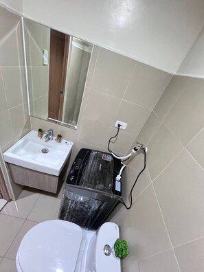 A bathroom with a white sink, mirror, and toilet. - Shore 3 1 BR 1006 (Pasay)
