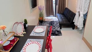 Zona pranzo moderna con tavolo nero, sedie rosse e un divano nero sullo sfondo.