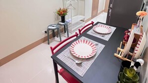 Zona pranzo con tavolo nero, sedie rosse e un appendiabiti bianco.