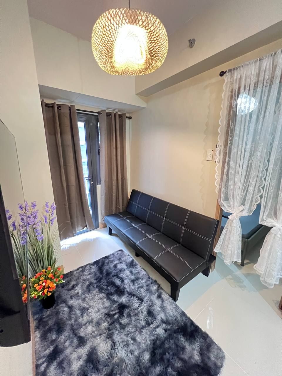 Un salón moderno con un sofá de cuero negro, una alfombra mullida y una planta decorativa.