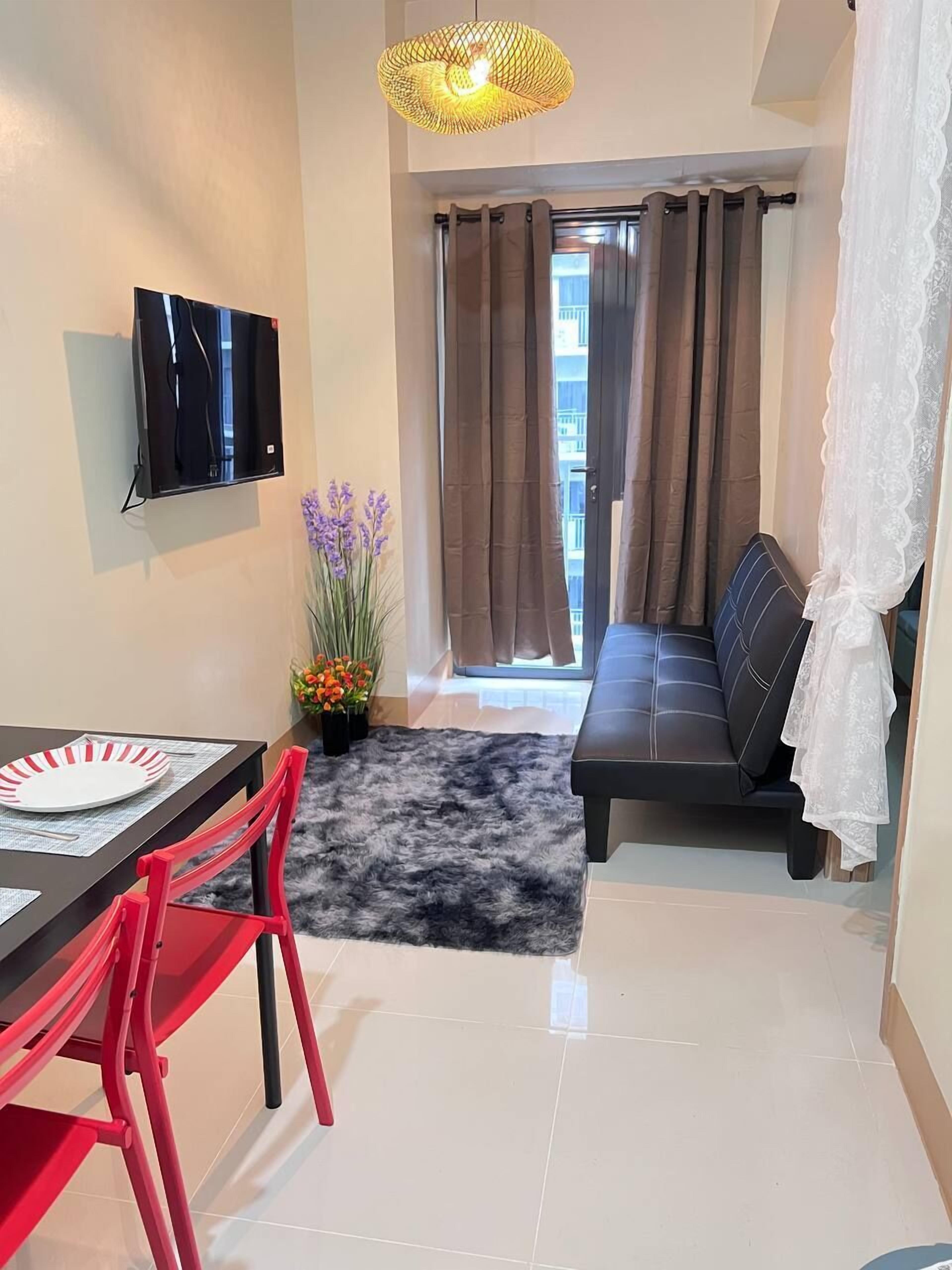 Un salon moderne avec un téléviseur à écran plat, un canapé, une table à manger avec des chaises et un petit tapis.
