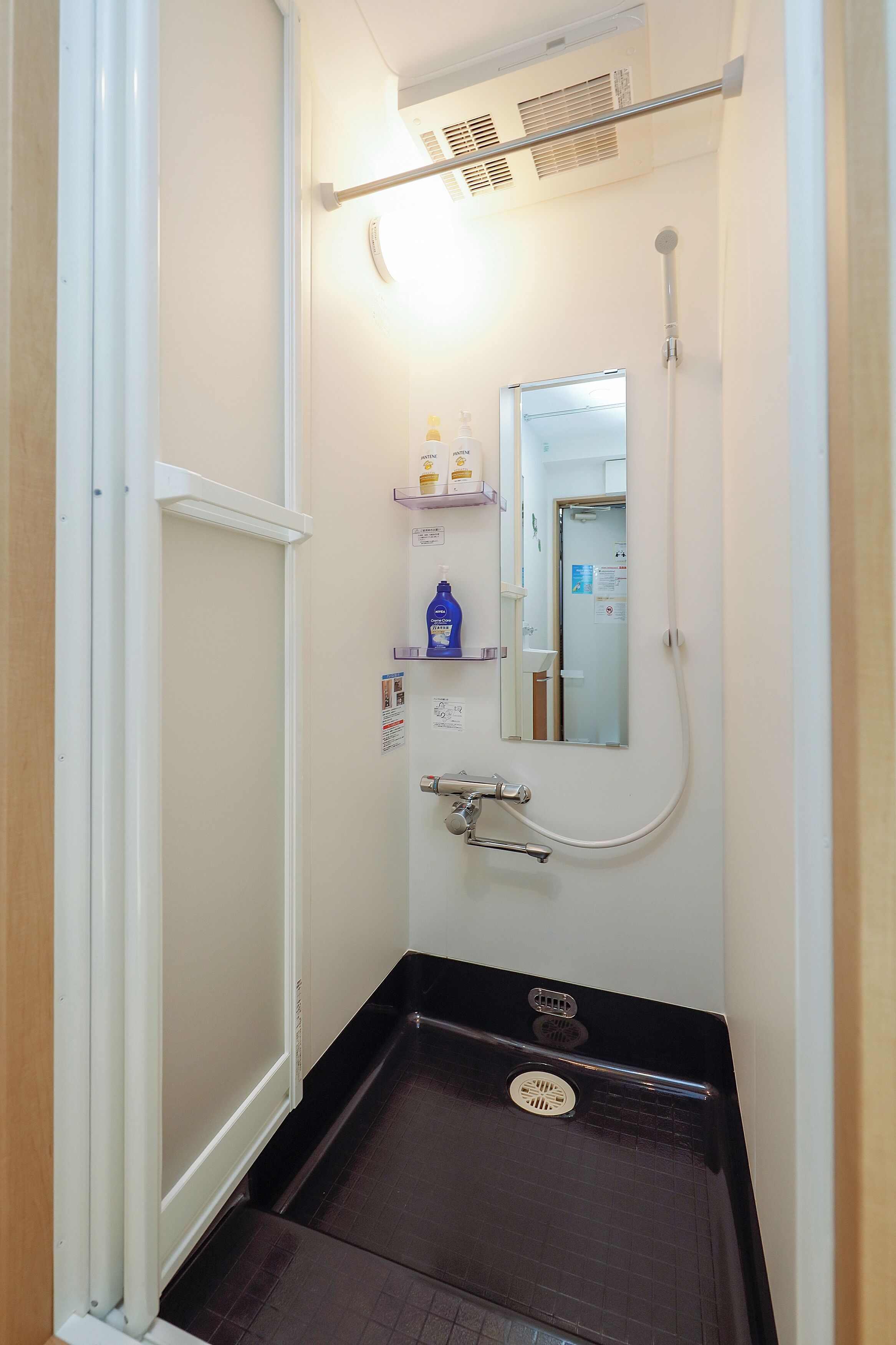 A small bathroom with a shower, a sink, and a mirror.