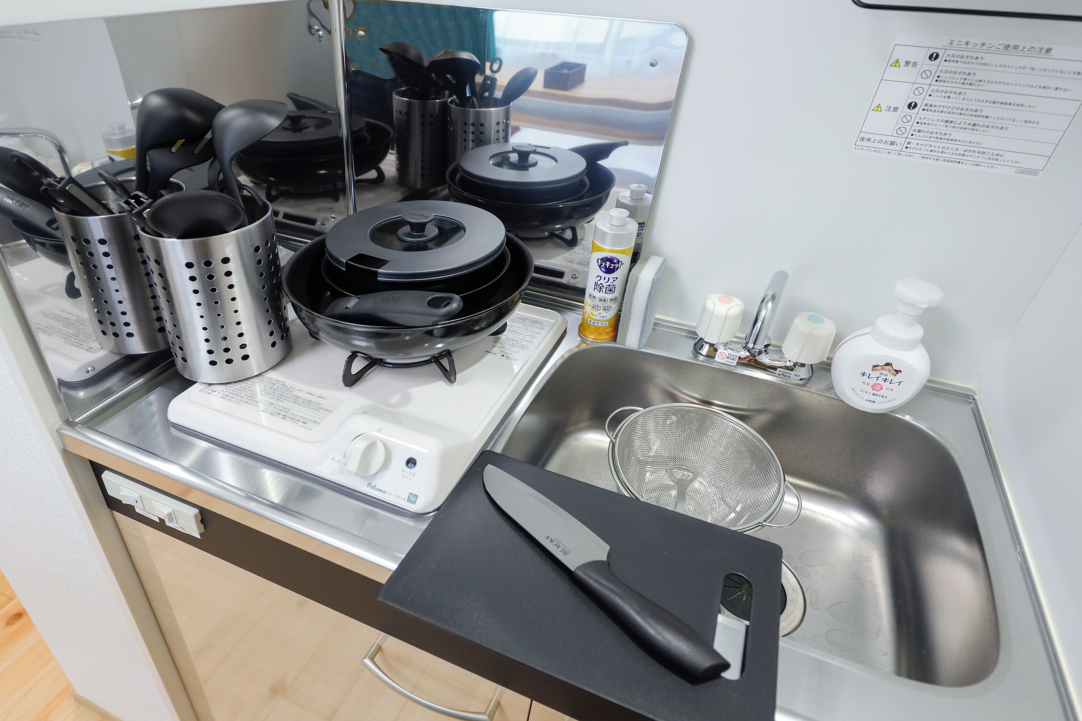 A kitchen with a stove, pots, a knife, and a sink.