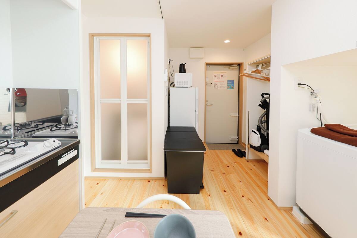 A modern kitchen with a stove, refrigerator, and a dining area with a table and chairs.