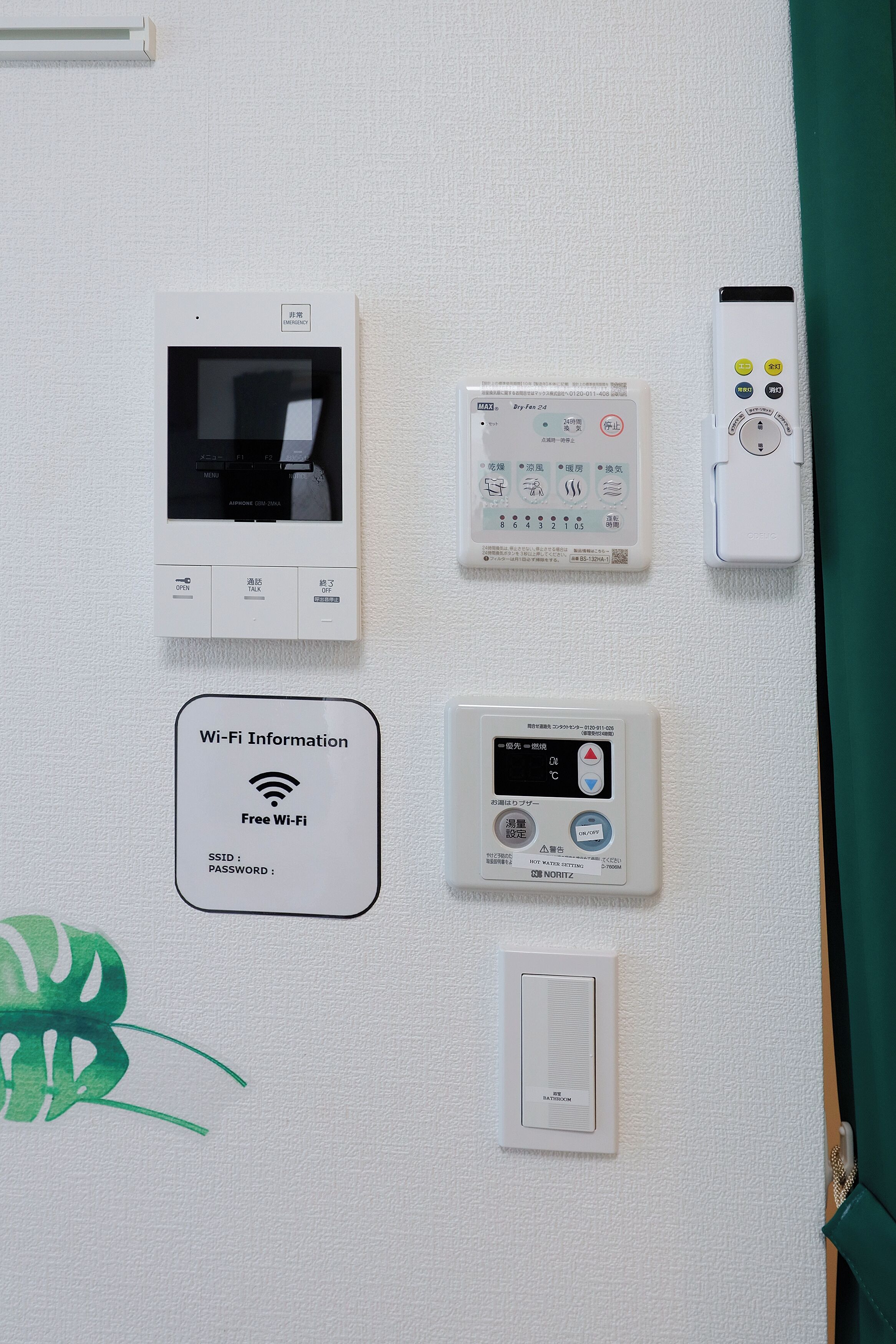 Un panneau de commande fixé au mur, doté de divers appareils, notamment un thermostat, un panneau d’affichage indiquant les informations Wi-Fi et une télécommande.
