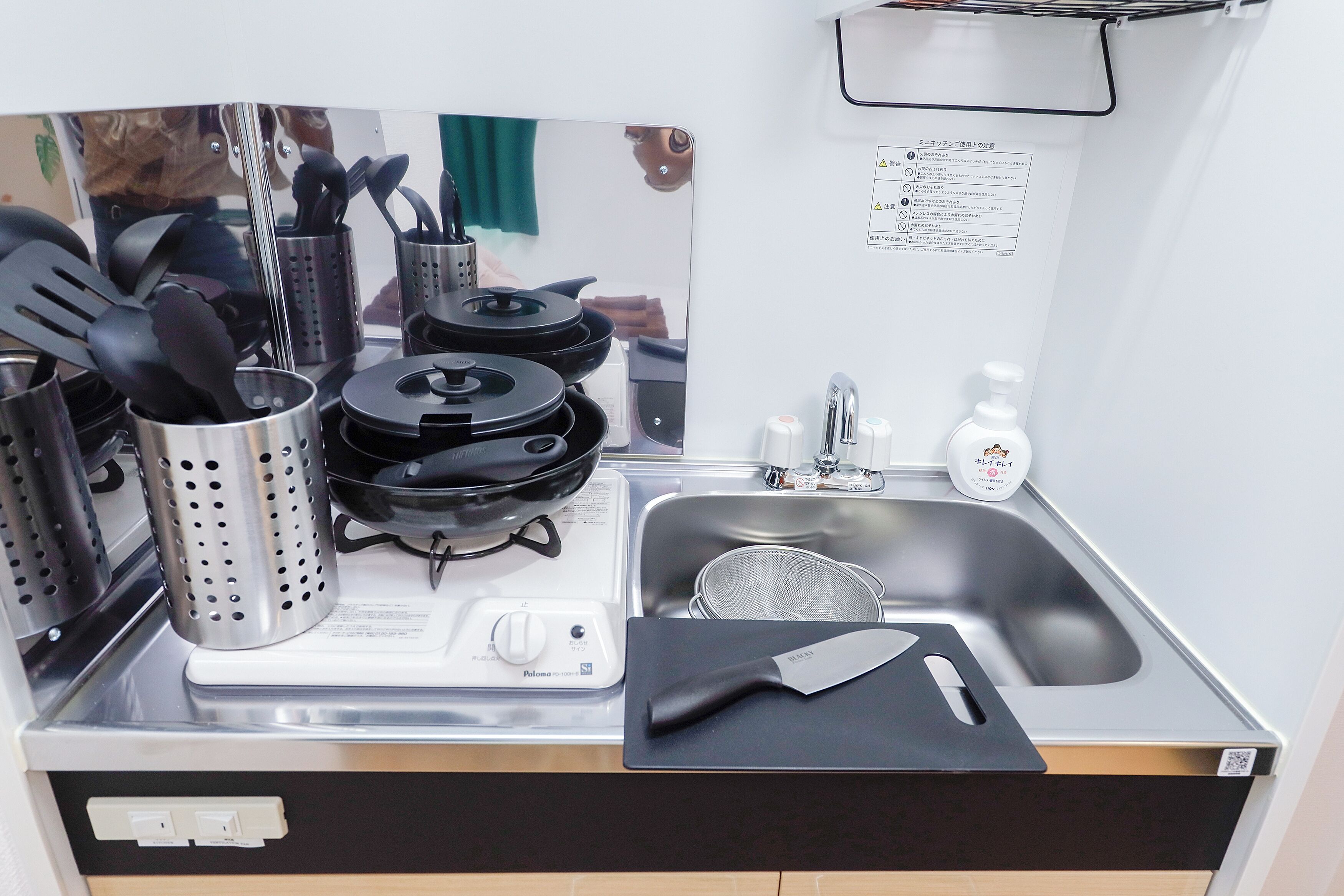 A compact kitchen with a stove, sink, and utensils.