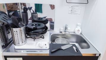 A compact kitchen with a stove, sink, and utensils.