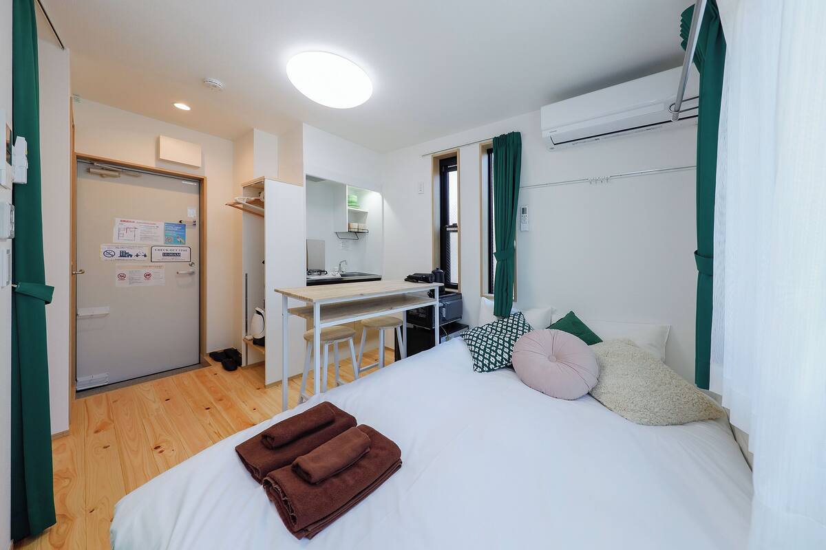 A hotel room with a bed, a desk, and a kitchenette.