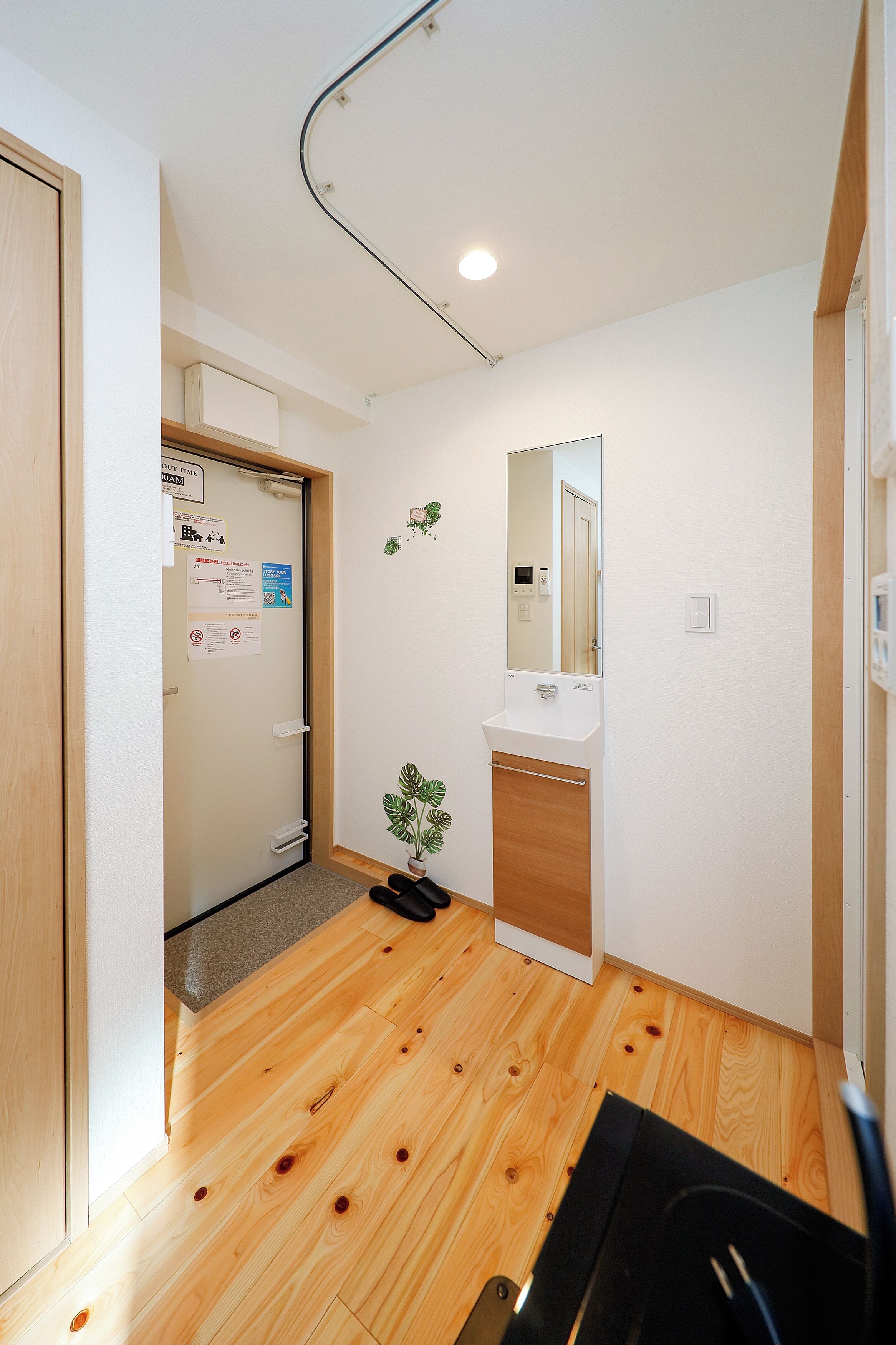 A small, clean room with wooden flooring, a white sink, and a mirror.