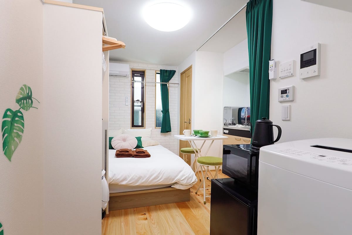 A compact hotel room with a bed, a small kitchenette, a microwave, and a refrigerator.