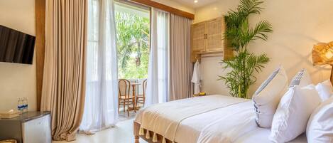 A bedroom with a bed, a small table with bottles, a chair, and a plant.