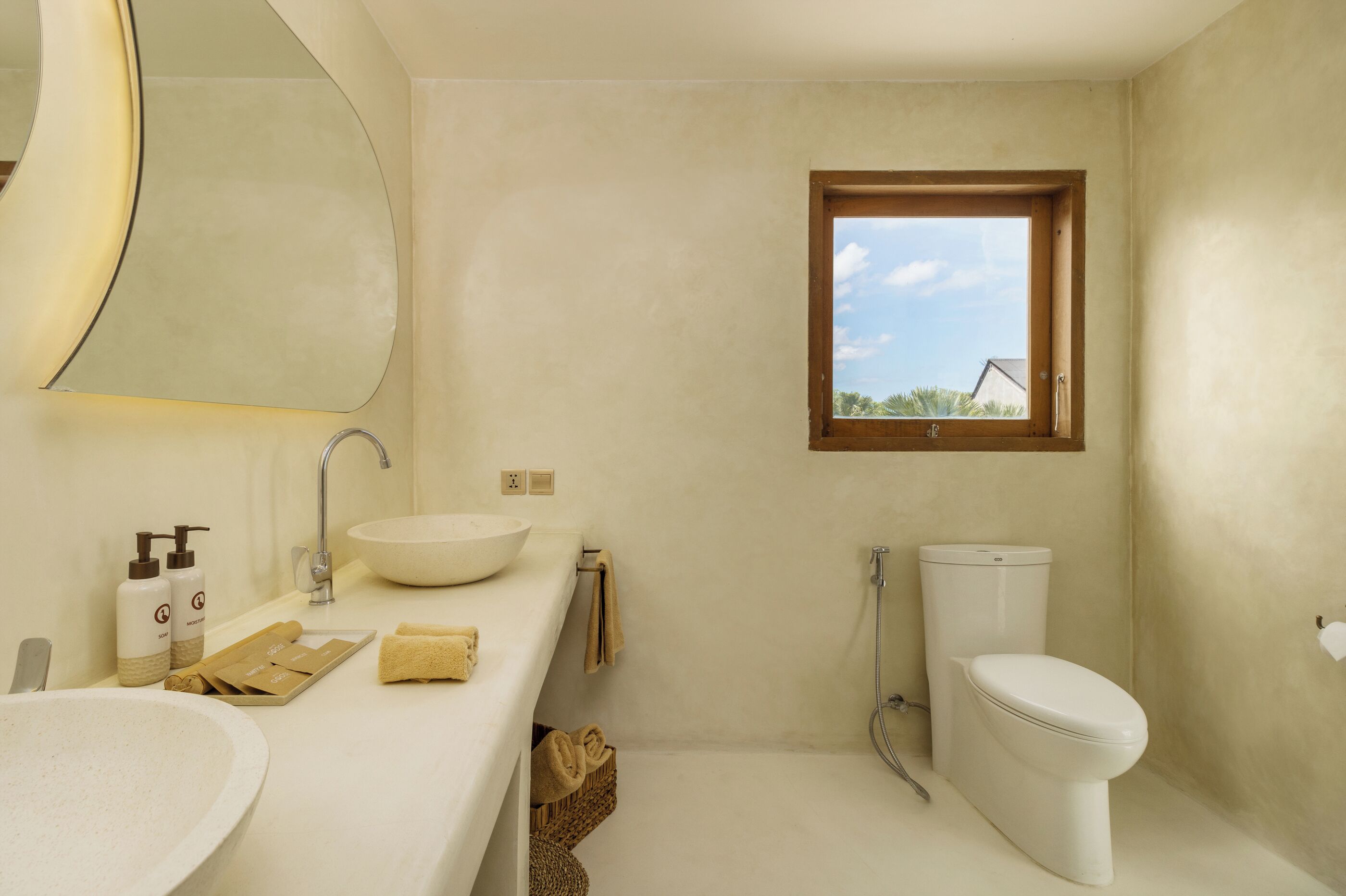 Une salle de bain avec un grand miroir, un lavabo, des toilettes et une fenêtre.