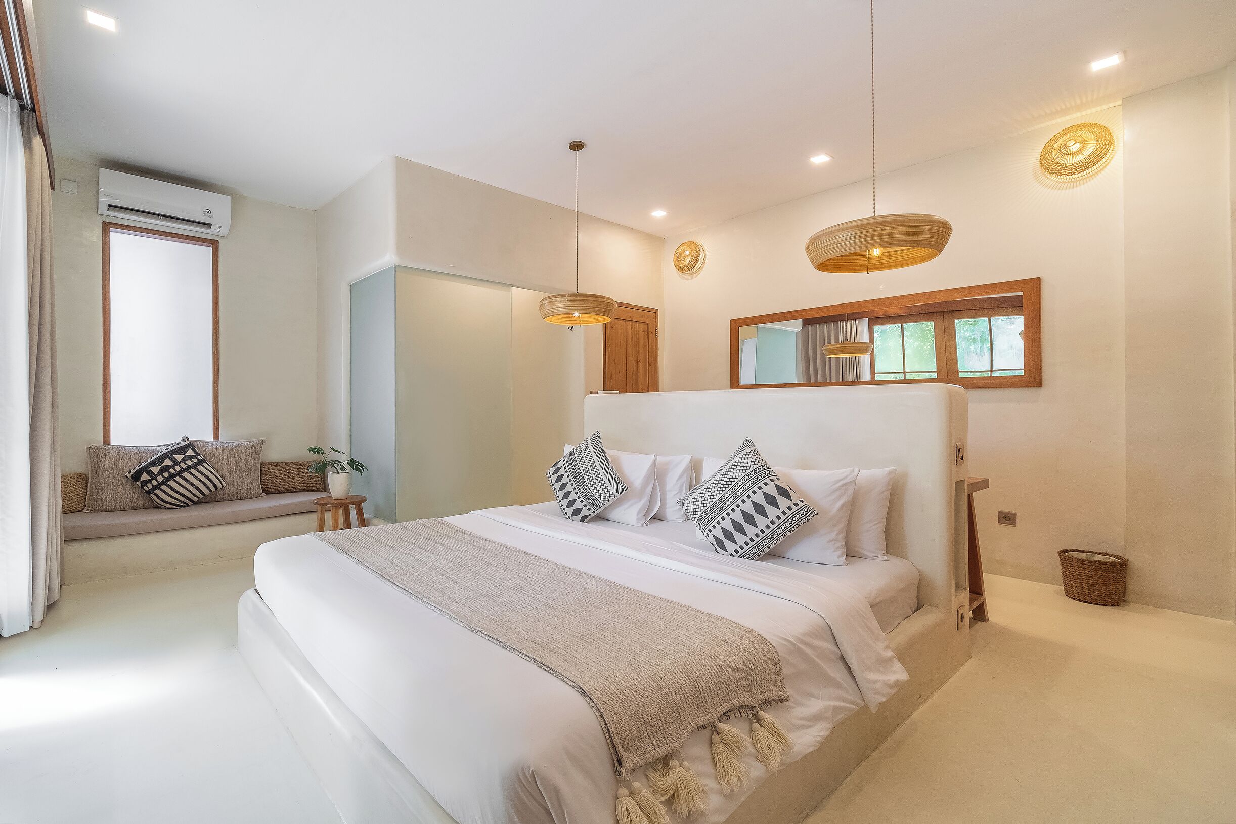 A modern bedroom with a large bed, a built-in bench, and a large window.