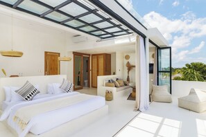 A modern bedroom with a large bed, a sofa, and a balcony with a glass ceiling. - White Goose Boutique Hotel (Tibubeneng)