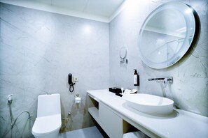 A modern bathroom with a toilet, sink, and mirror. - Club House Hotel Ayodhya (Faizabad)