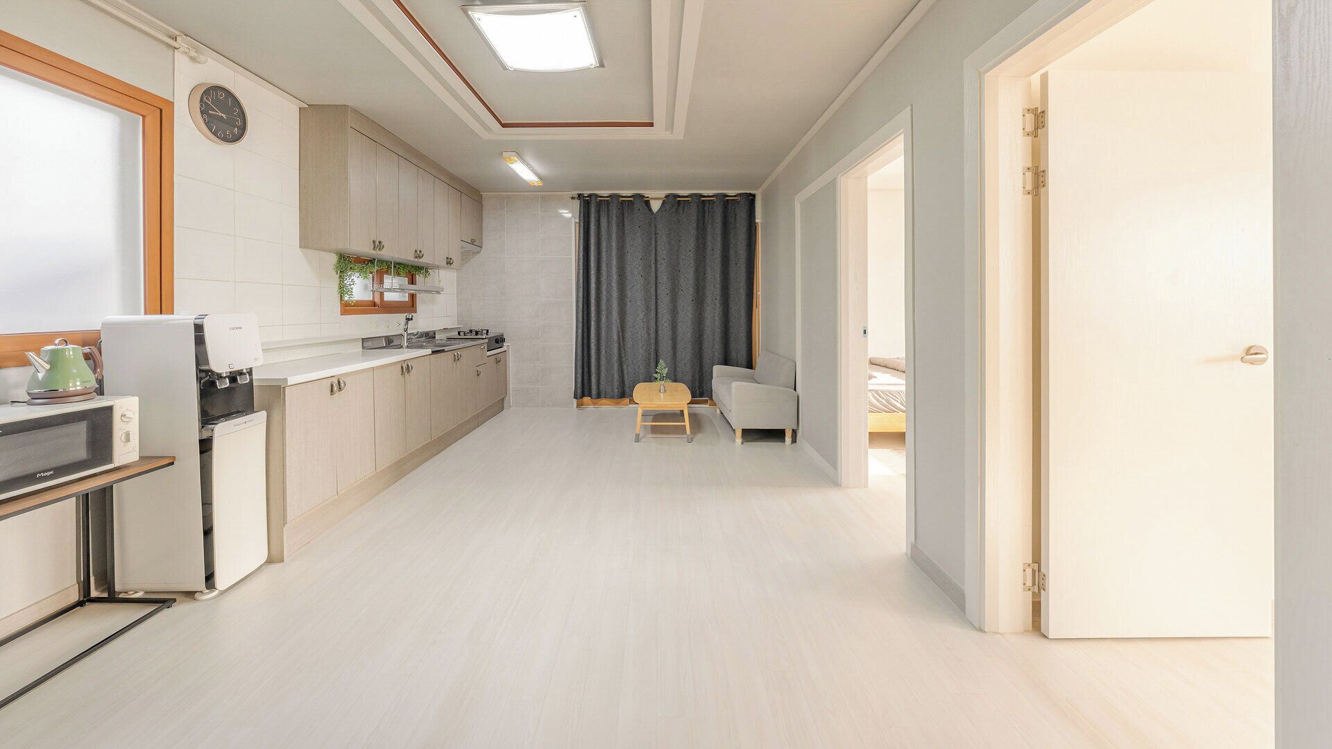 Una cocina moderna con microondas, estufa y armarios, que da paso a un comedor con mesa y sillas.