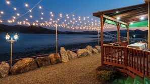 A wooden deck with a table and chairs, overlooking a body of water with mountains in the background. - Namhae Bada Yanolja Pension (Namhae)
