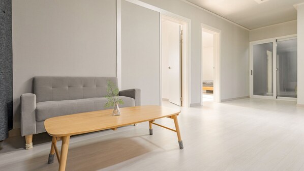 Een moderne woonkamer met een grijze bank, een houten salontafel en een vaas met een plant.