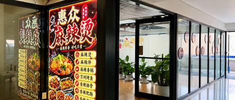 A restaurant with a bright neon sign advertising various dishes.