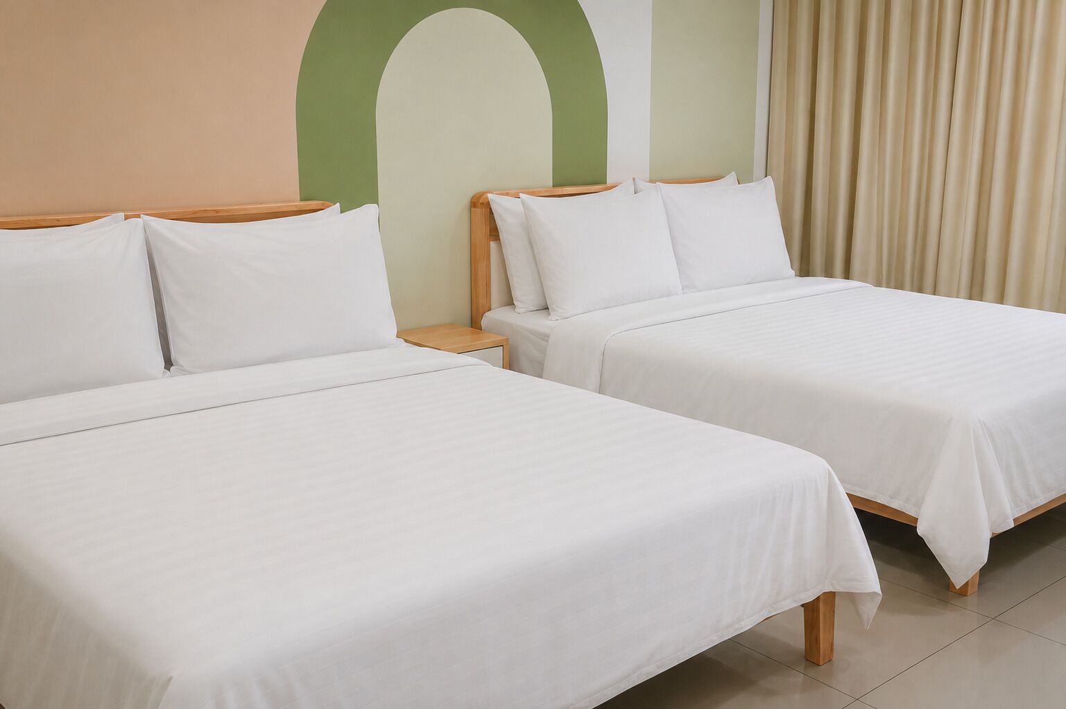 Two single beds with wooden frames and white bedding in a room with a green and beige wall.