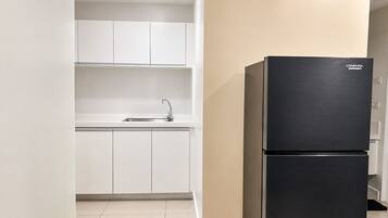 A kitchen with white cabinets, a black refrigerator, and a sink.