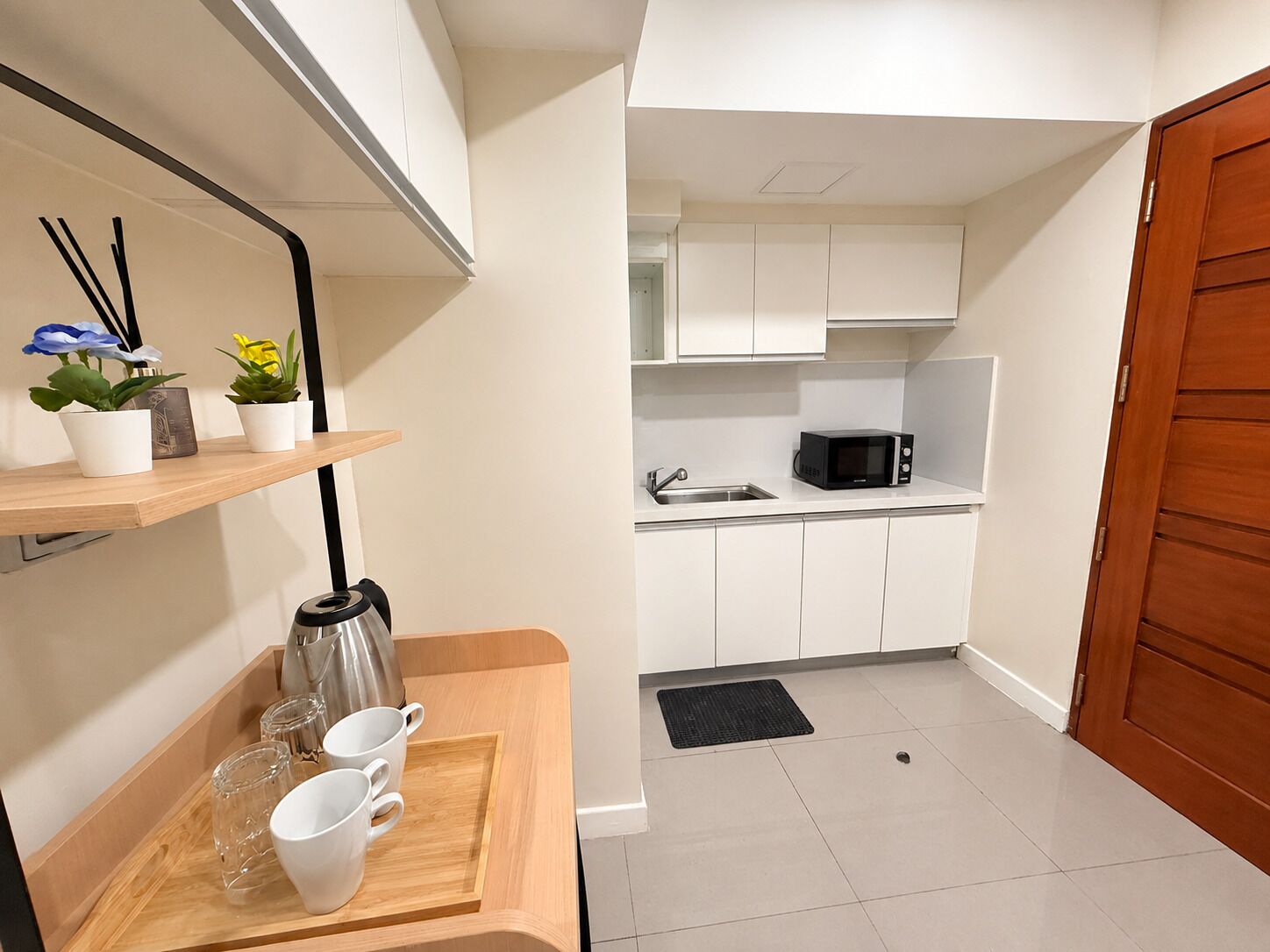 Una cocina compacta con alacenas blancas, microondas y cafetera sobre una encimera de madera.