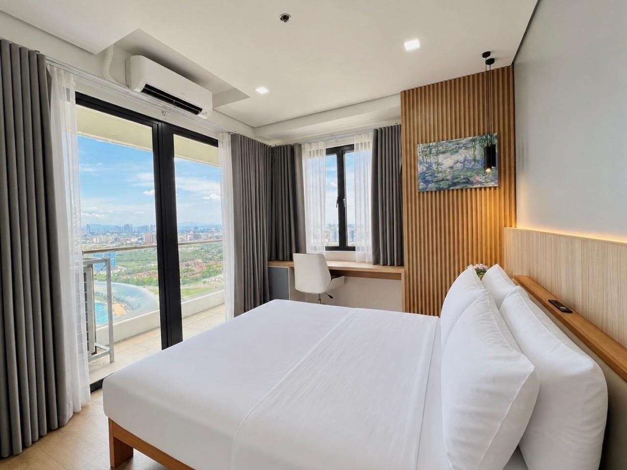 A hotel room with a large bed, a desk, and a view of the city.