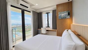 A hotel room with a large bed, a desk, and a view of the city.