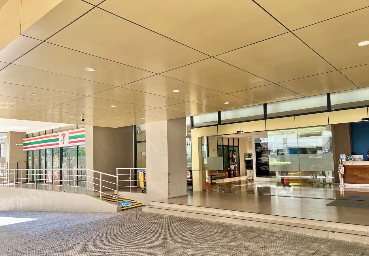 A spacious indoor area with a 7-Eleven store, a reception desk, and a staircase leading to an upper level.