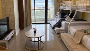 A hotel room with a balcony, a TV, a round table, and bunk beds. - Sapphire Seaview Park (Parañaque)