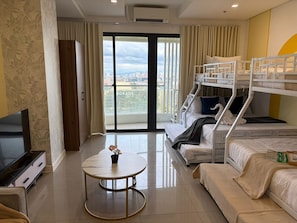 A hotel room with a balcony, a TV, a round table, and bunk beds. - Sapphire Seaview Park (Parañaque)