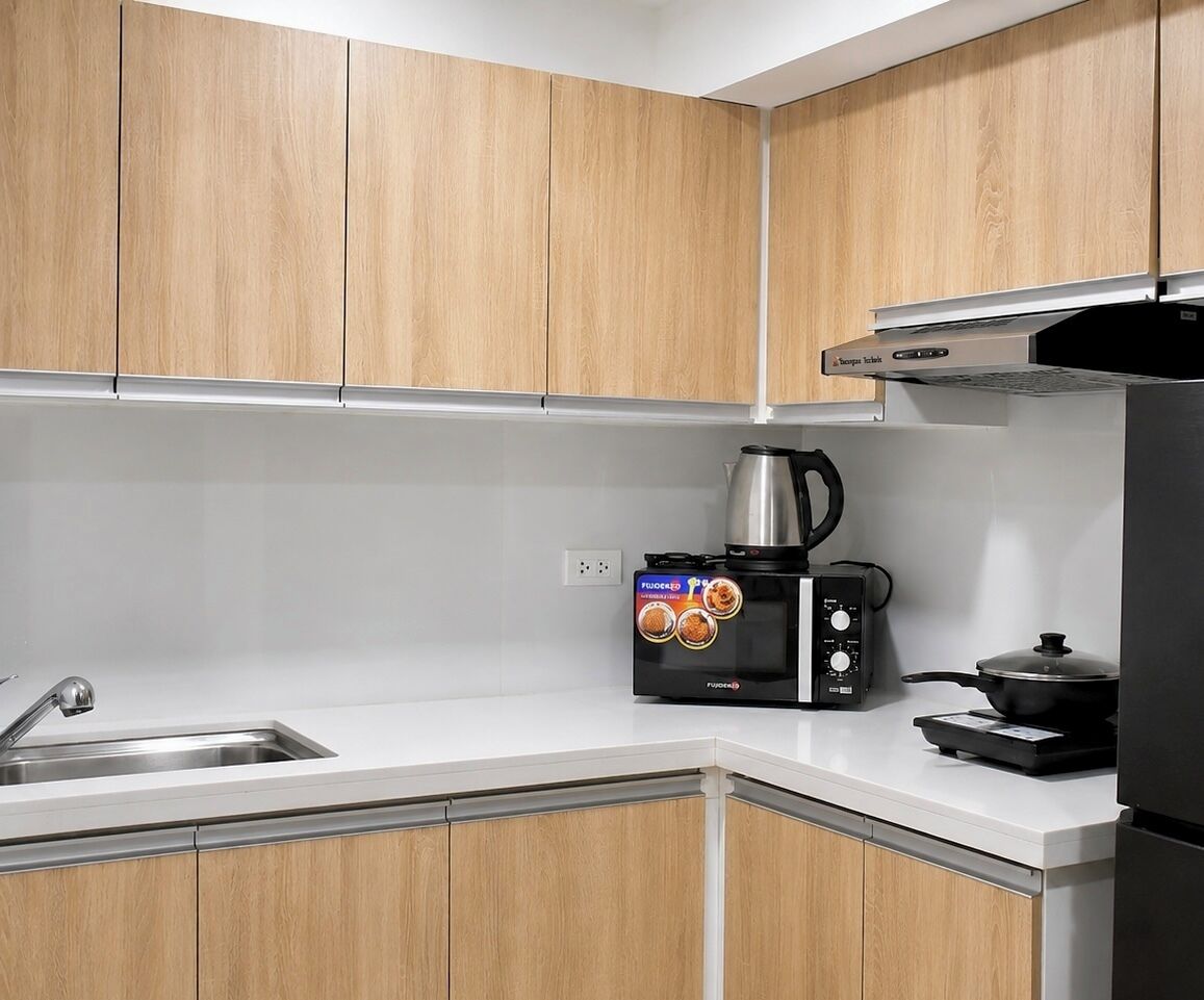 A kitchen with wooden cabinets, a stainless steel sink, a coffee maker, and a stove.