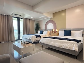 A modern hotel room with two beds, a small table, and a view of the outdoors. - Sapphire Seaview Park (Parañaque)