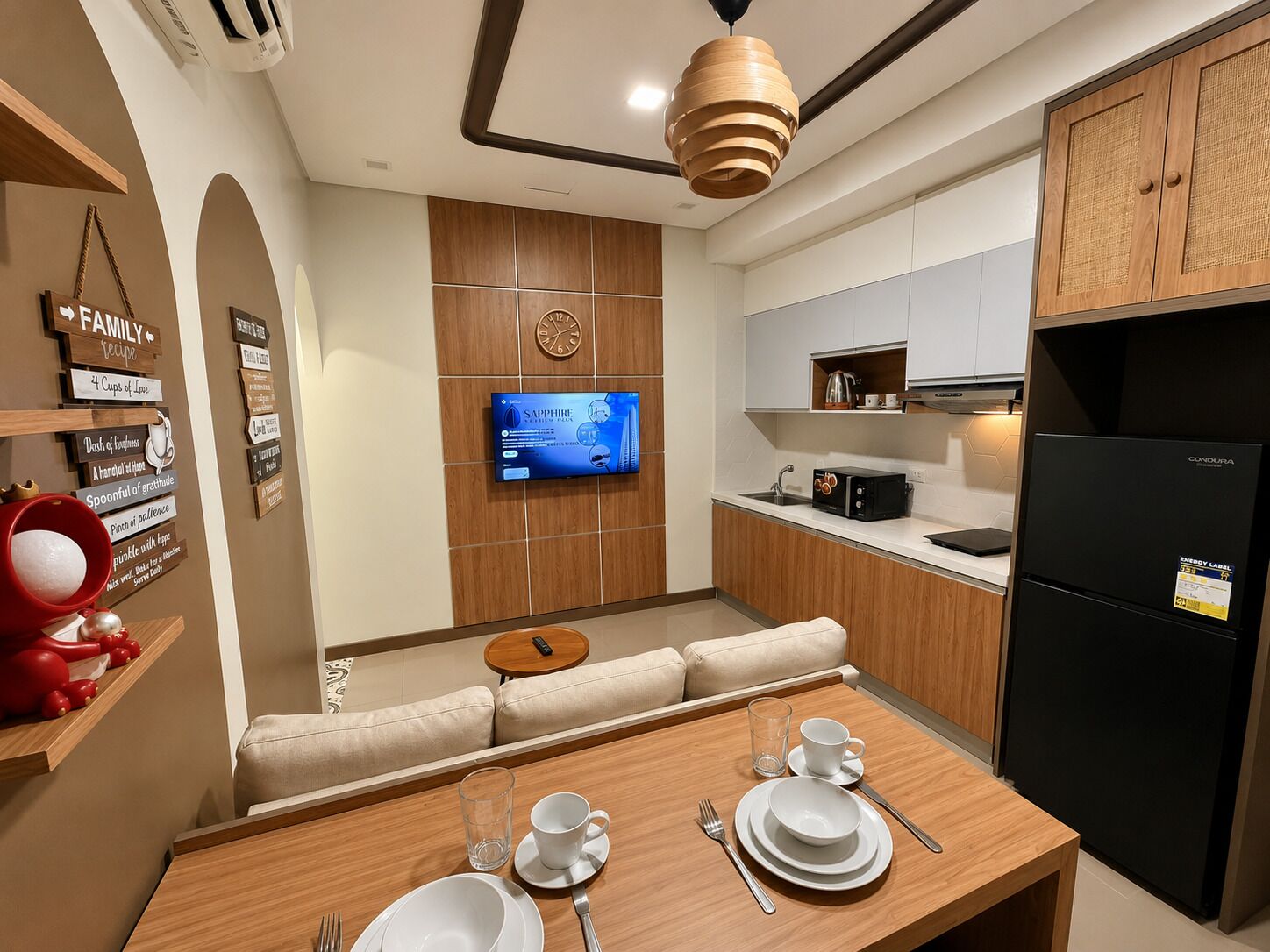 A modern kitchen with a dining area, wooden cabinets, a built-in TV, and a refrigerator.