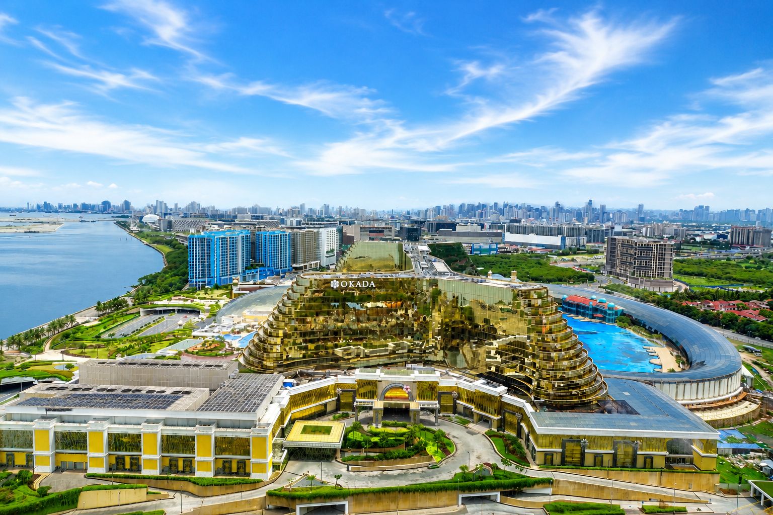 A modern hotel complex with a central atrium, multiple floors, and a waterfront view.