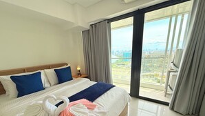 A hotel room with a large bed, a view of the city, and a balcony. - Sapphire Seaview Park (Parañaque)