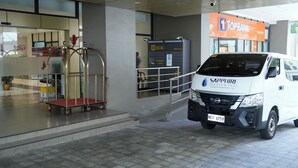 A white van with "SAPPHIRE SEAVIEW PARK" and a license plate "NEV 6759" parked in front of a building with an orange sign that reads "TOPBANK A RURAL BANK". - Sapphire Seaview Park (Parañaque)